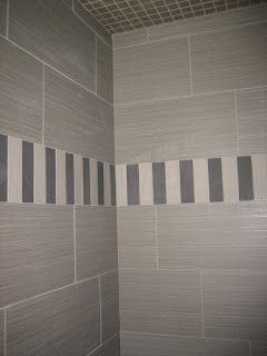 Gray tiled shower with a stripe of alternating gray, white, and dark gray tiles