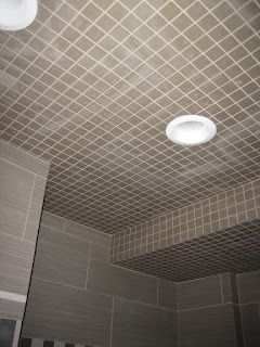 Gray tiled ceiling with two recessed lights, corner of a bathroom