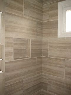 Bathroom corner with tan, textured tile, built-in shelf, and window