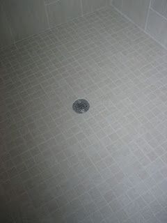Gray tiled shower floor with drain in the center