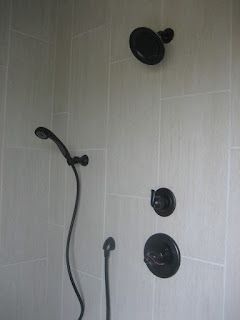 Black shower fixtures on light gray tiled wall.