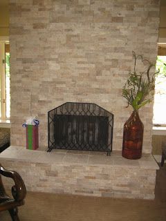 Stone fireplace with black screen, vase of greenery, and gift bag