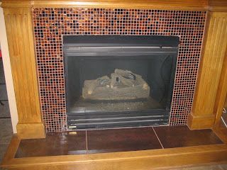 Fireplace with brown tiled surround and wooden mantel.