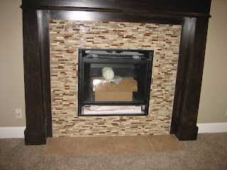 Fireplace with dark wood trim and mosaic tile surround; black fireplace insert.