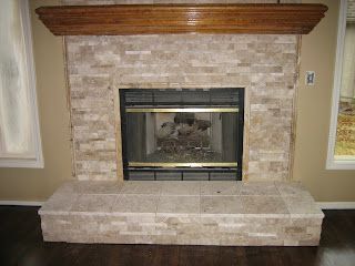 Fireplace with tan stone surround, dark wood mantel, and hearth.