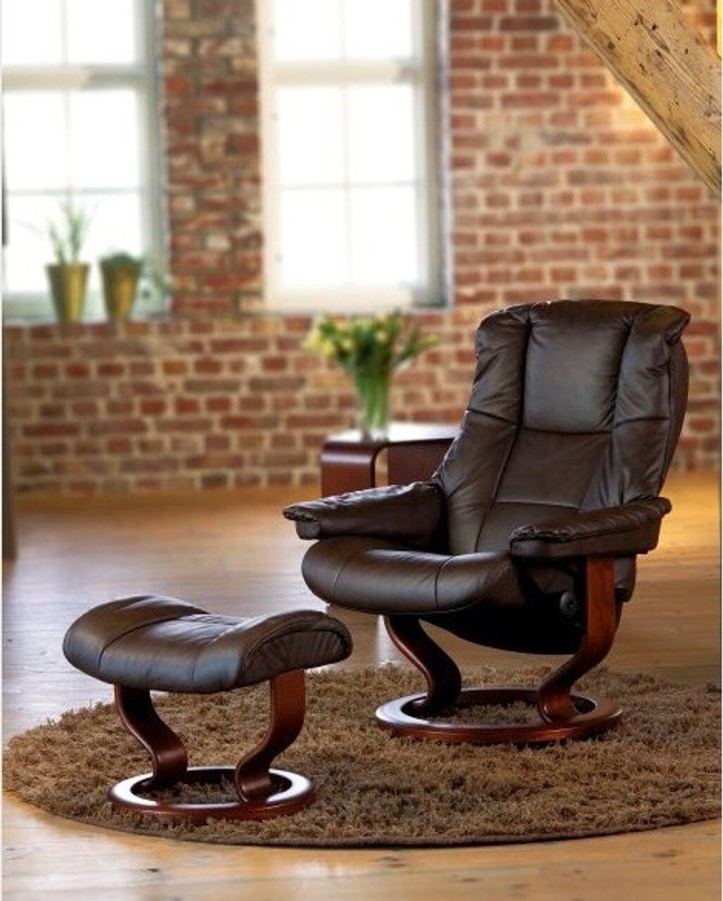 Black modern leather recliner and ottoman on a throw rug in a large open livingroom