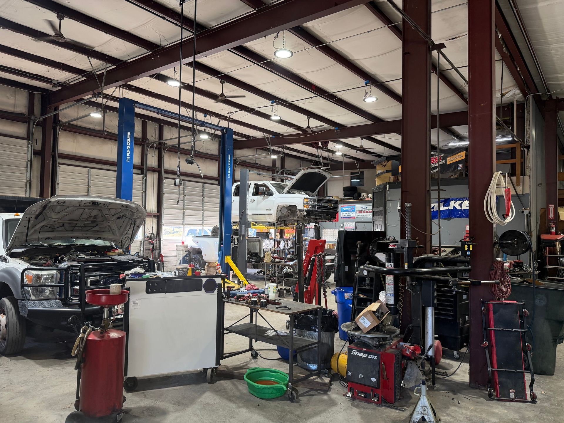 Auto repair shop with cars on lifts, tools, and equipment inside a large garage