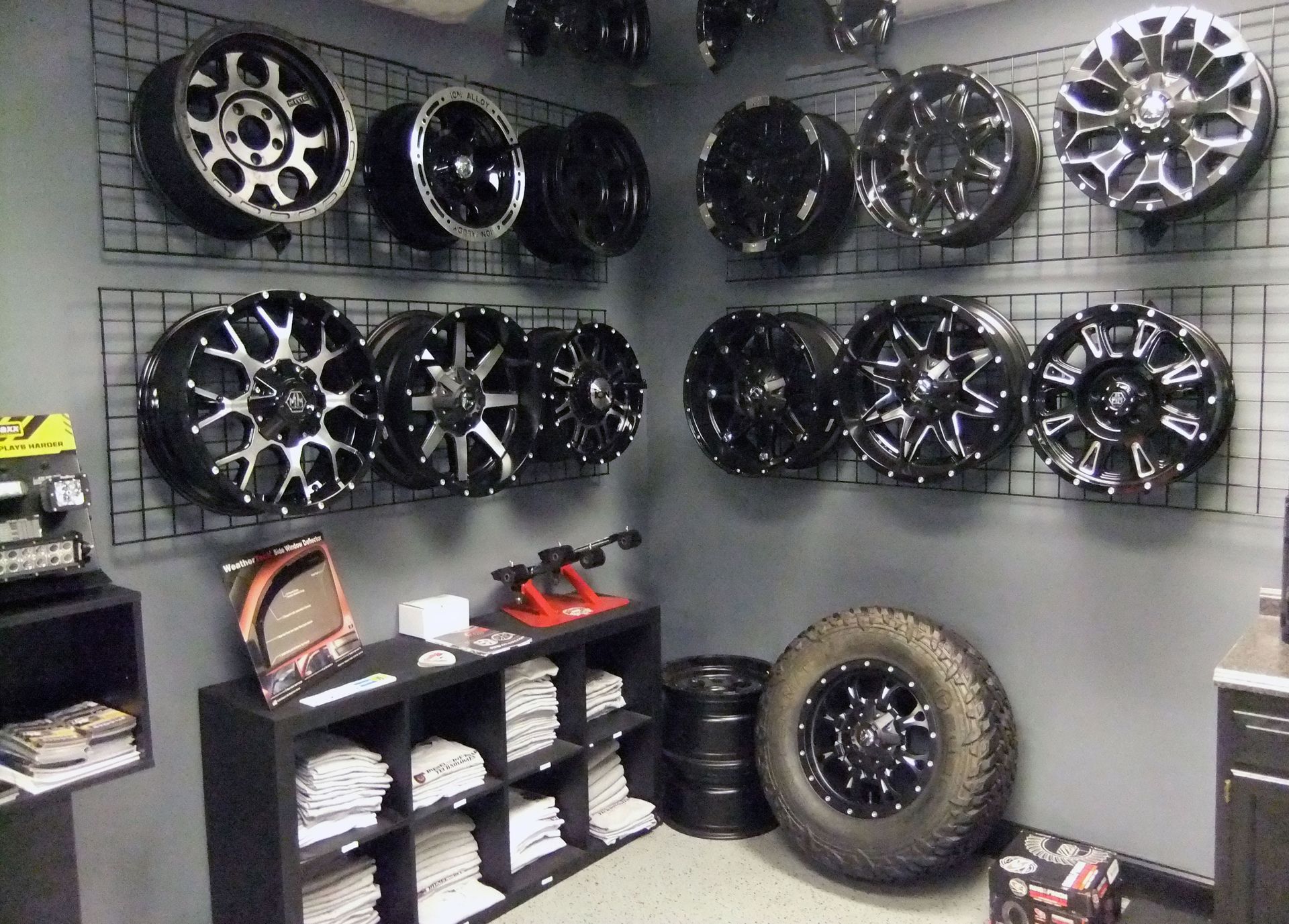 Wheel display in a shop, with rows of alloy rims and a few tires on the floor.