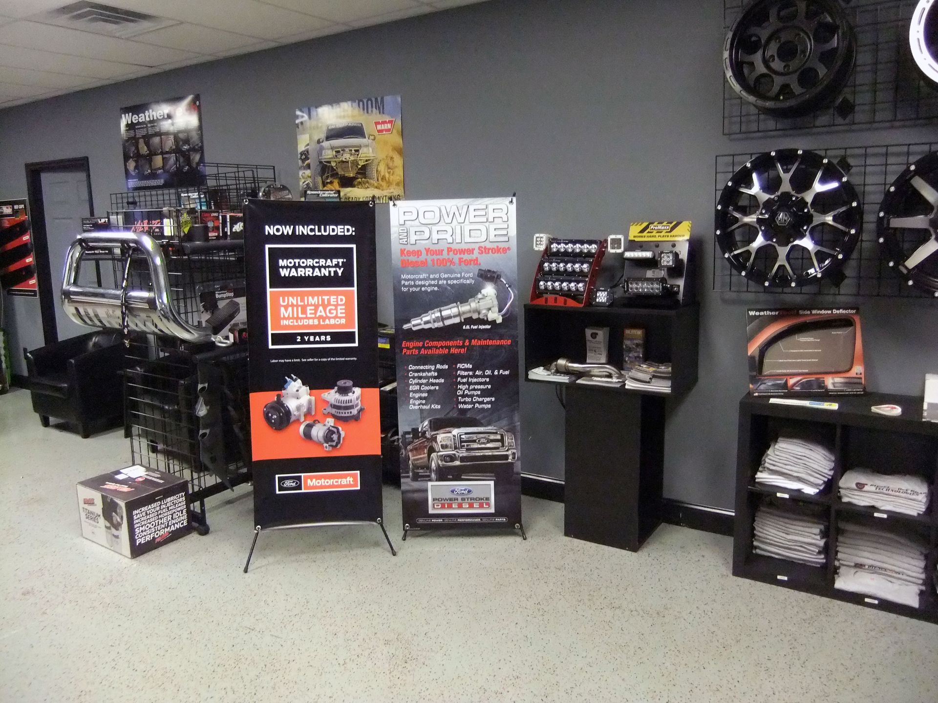 Display of car audio and wheel accessories in a showroom, with banners, shelves, and black display stands.