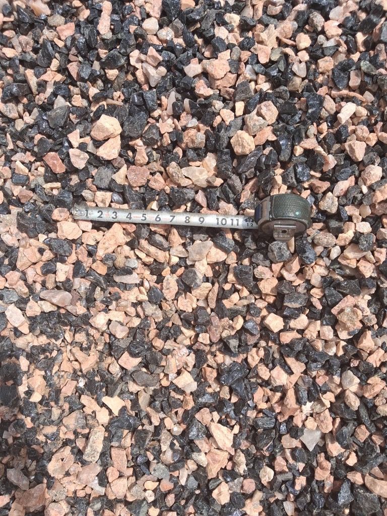 Gravel mixed with black and tan stones, a tape measure on top.