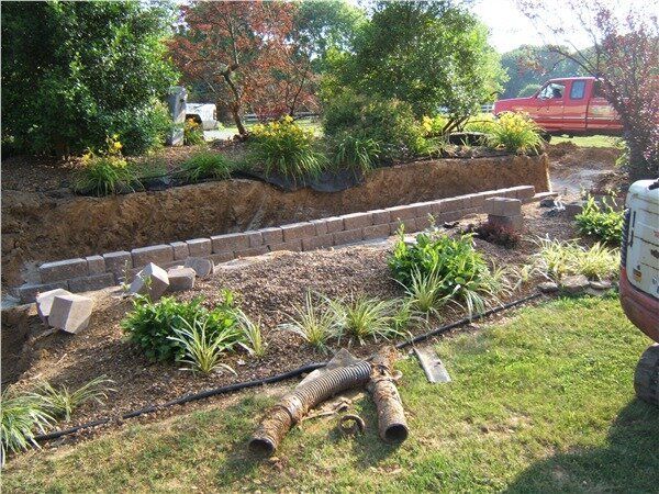 Stone retaining wall being built near a garden