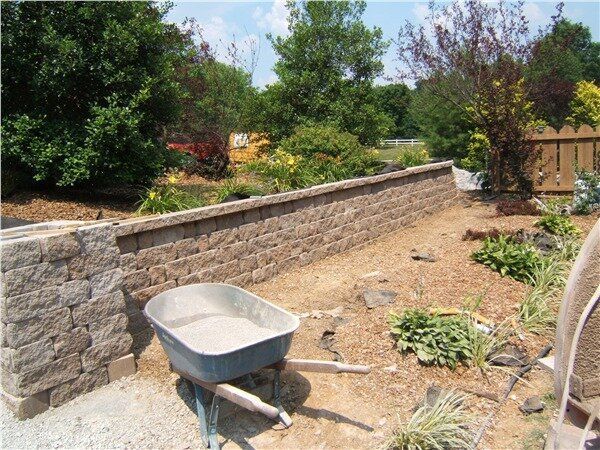 A wheelbarrow is sitting in front of a a stone wall.