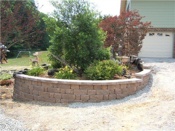 A brick wall surrounds a garden in front of a house