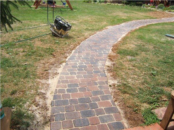 A brick walkway is being built in a yard