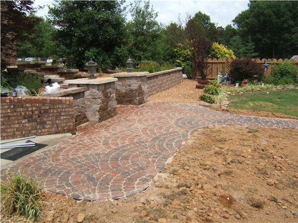A brick walkway leading to a fenced in yard