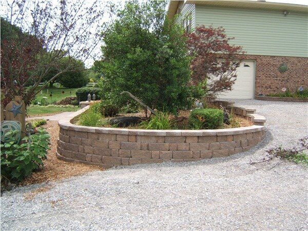A house with a custom retaining wall to the side and a gravel driveway