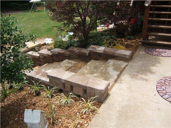 A stone patio with steps and a tree in the background