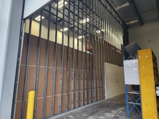 Industrial interior with metal framing, unfinished walls, and stacked blue and yellow equipment