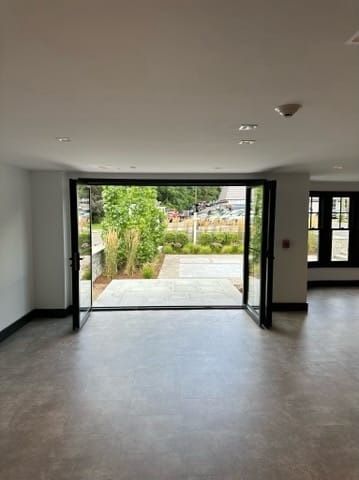Empty modern room with open double doors leading to a garden patio.