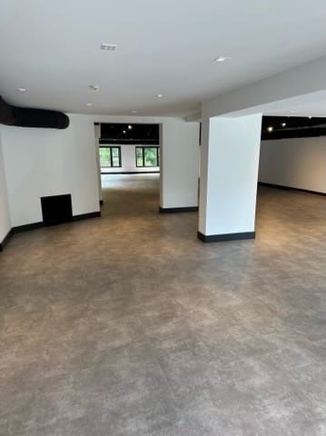 Empty modern room with gray floor, white walls, and recessed ceiling lights