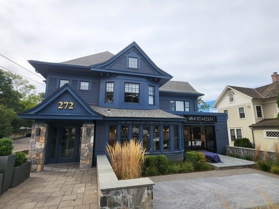 Blue two-story house with stone accents, a front porch, and the number 272 on the facade