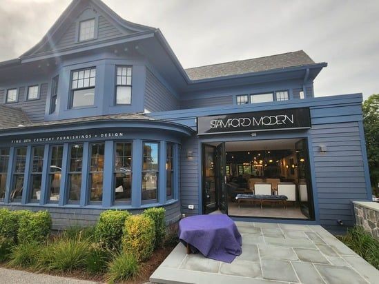 Blue storefront with a large bay window and open entrance on a cloudy day