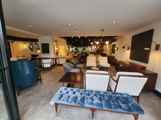 Cozy lounge with tufted blue bench, white chairs, wood tables, and warm pendant lighting