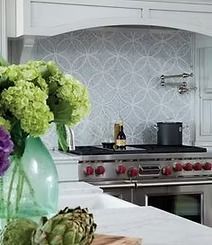 Kitchen with green flowers, a patterned backsplash, a stove, and artichokes on the countertop.