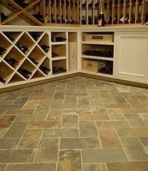 Wine cellar with wooden racks and stone tile floor.