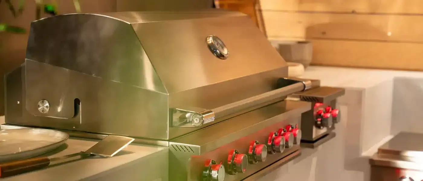 A stainless steel grill is sitting on a counter in a kitchen.