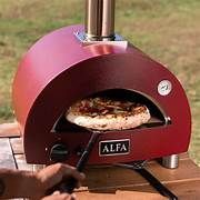 A pizza is being cooked in a red pizza oven.