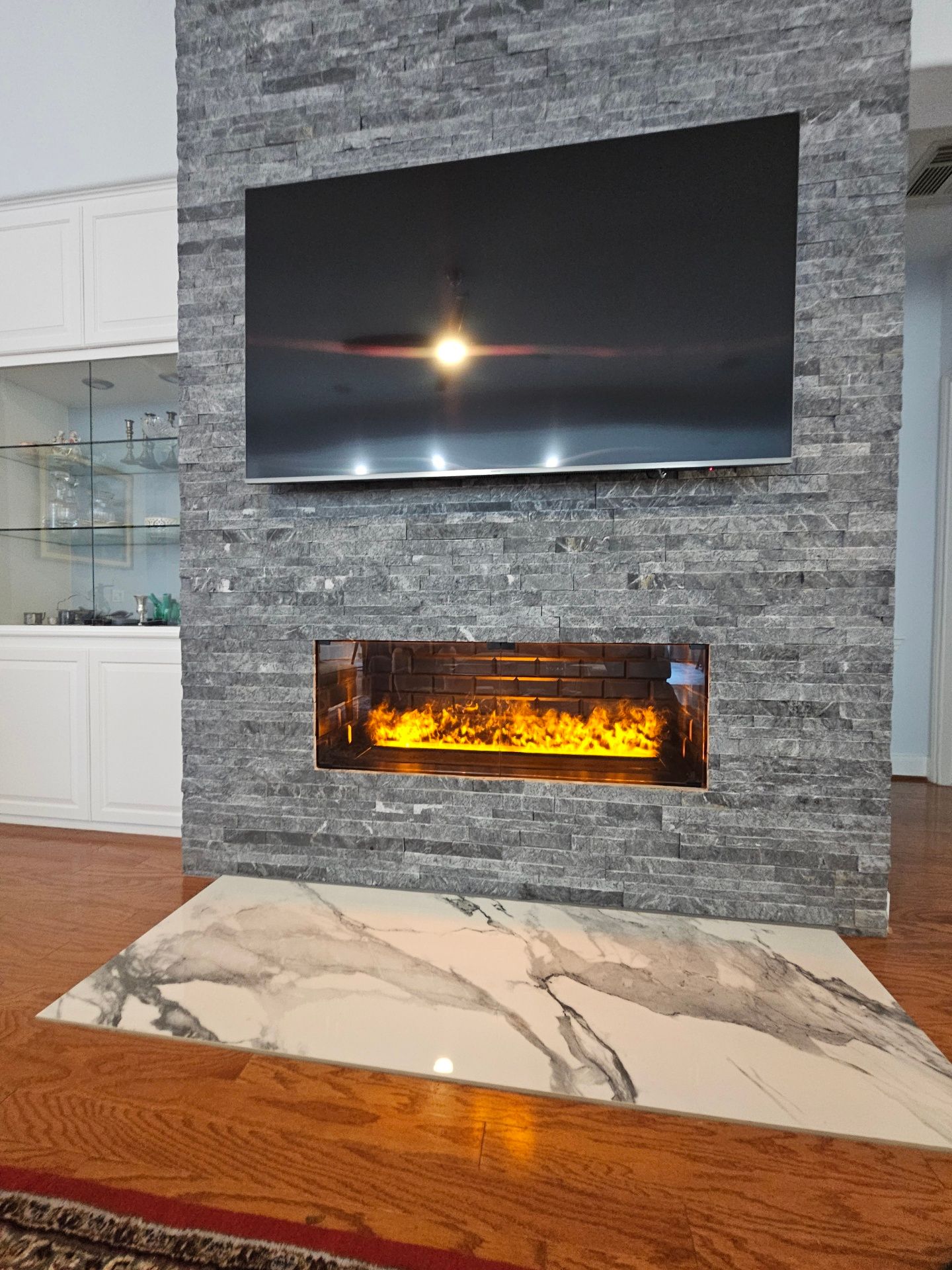 A living room with a fireplace and a flat screen tv on the wall.