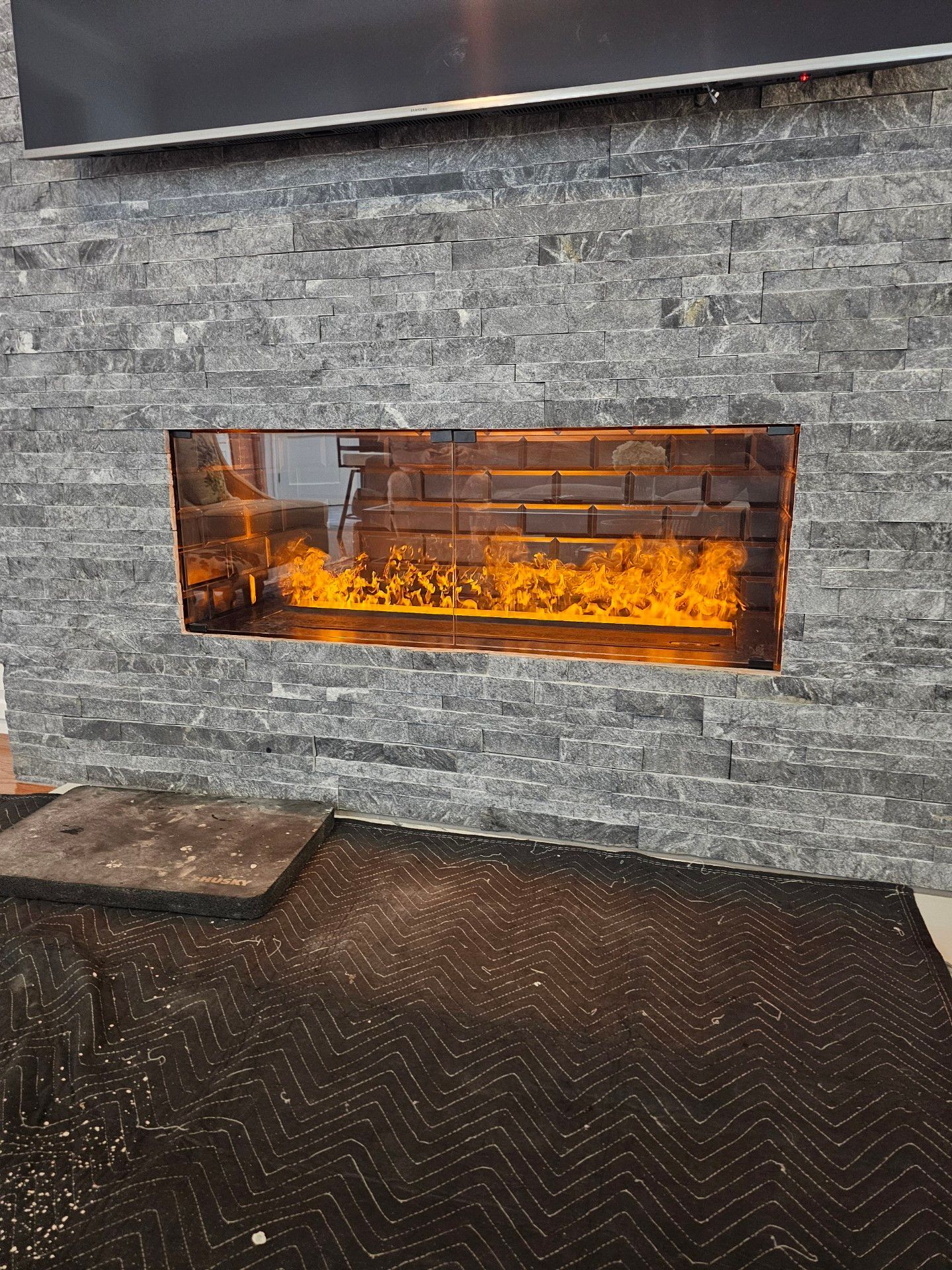 A fireplace is built into a brick wall with fire coming out of it.
