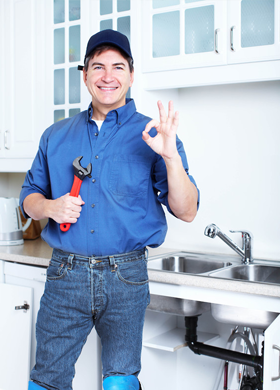 Plumber besides a kitchen sink showing a sign of okay