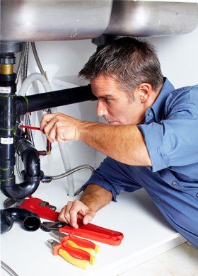 A plumber holding screw driver to fix a pipe