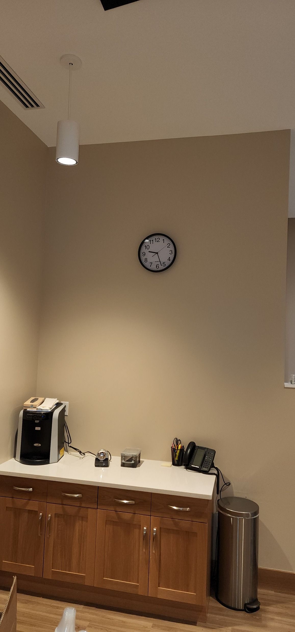 A kitchen with wooden cabinets and a clock on the wall.