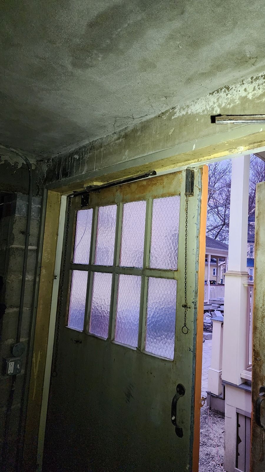 A door with a lot of windows is open in a room.