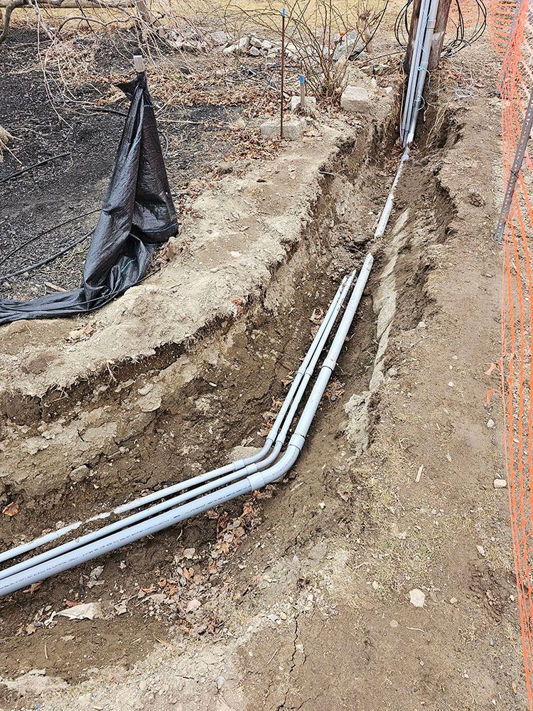 A bunch of pipes are laying in the dirt.