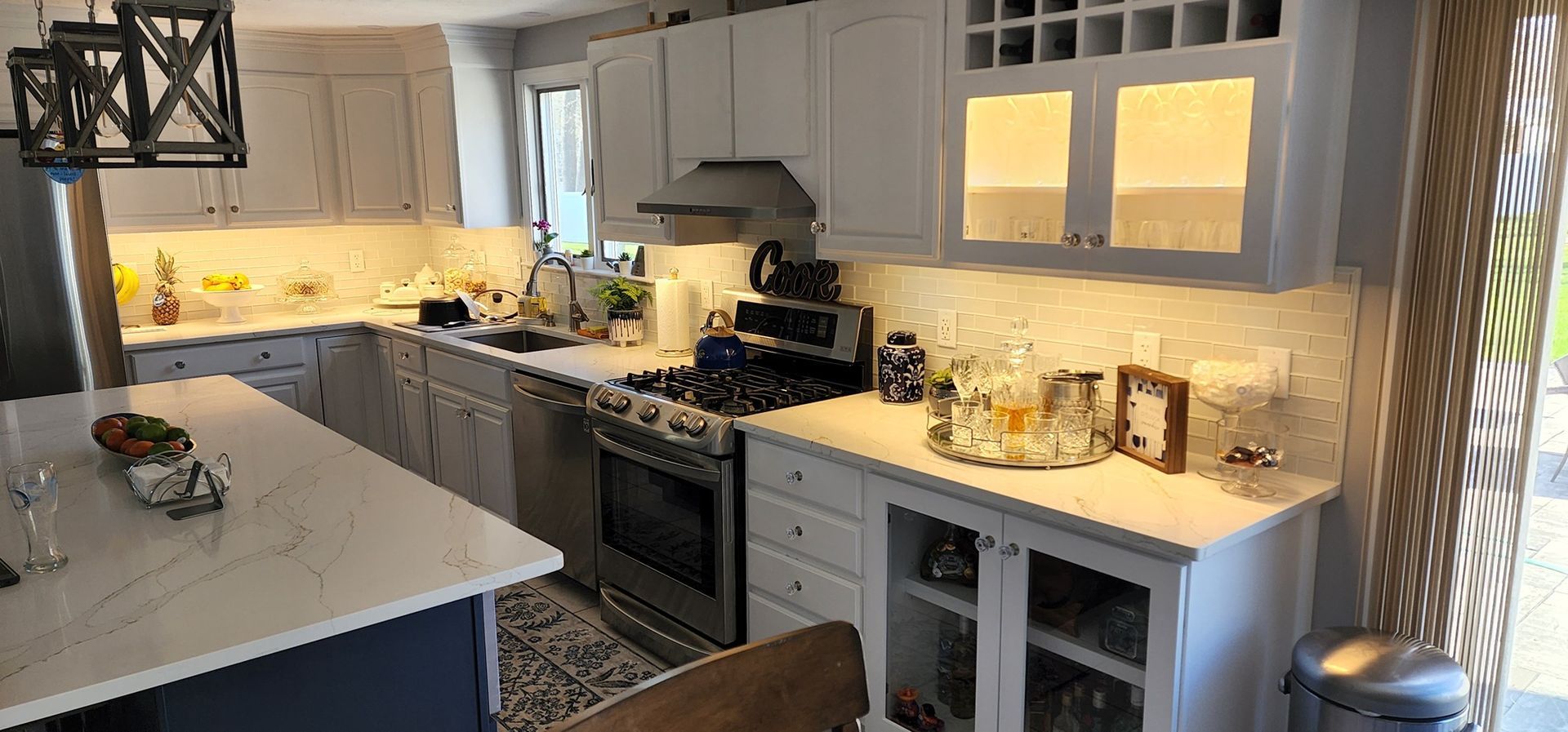 A kitchen with white cabinets , stainless steel appliances , and a large island.