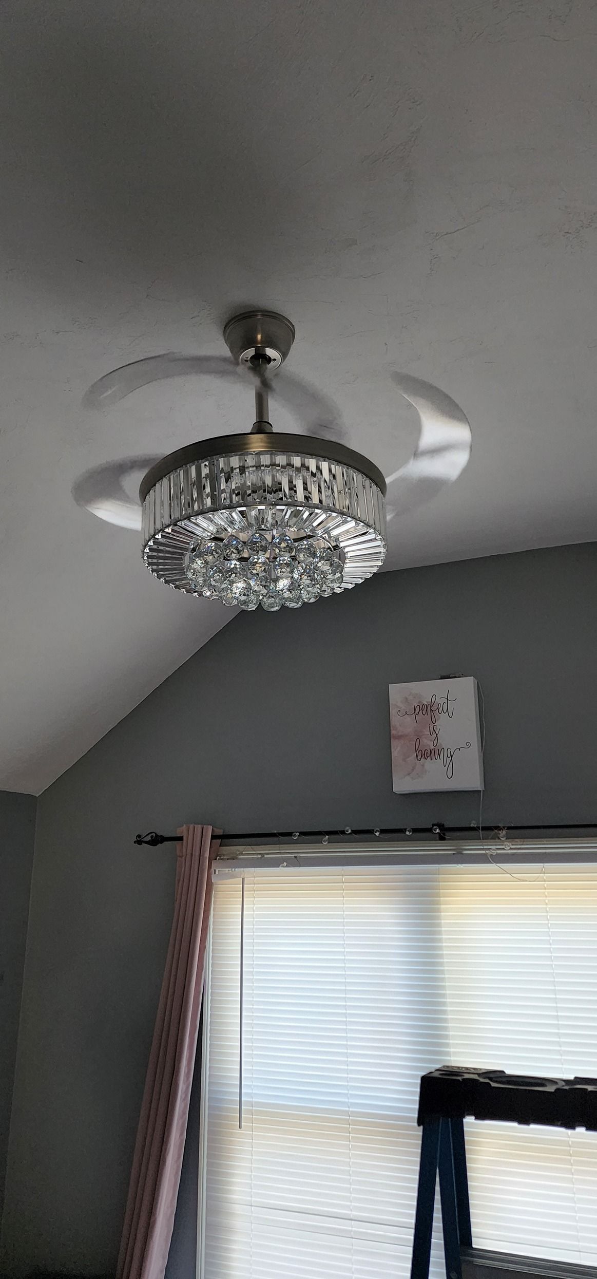 A ceiling fan is hanging from the ceiling in a room next to a window.