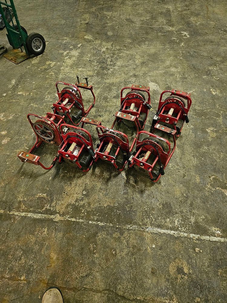 A bunch of red carts are sitting on top of a concrete floor.