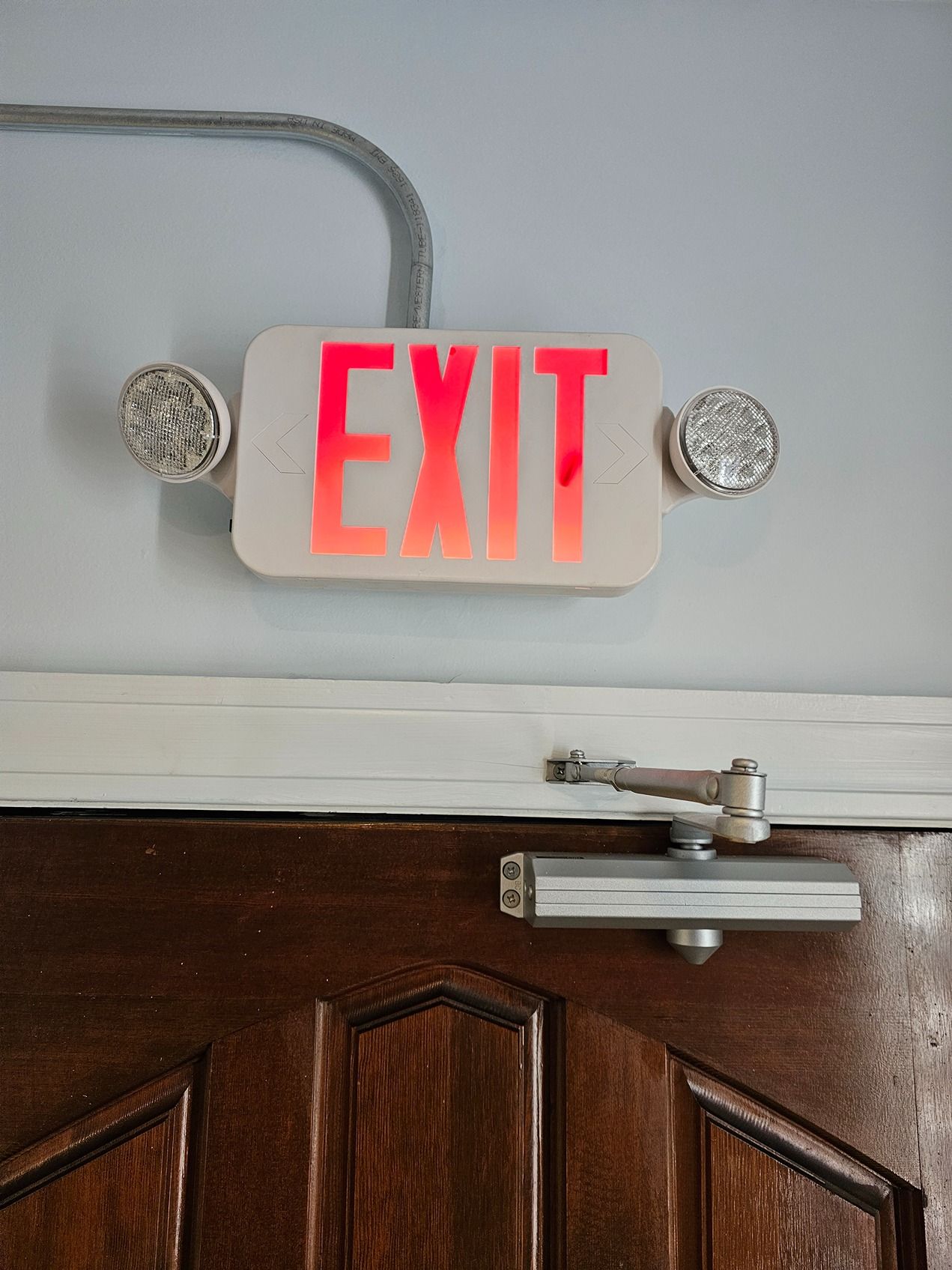 A red exit sign is hanging on a wooden door.