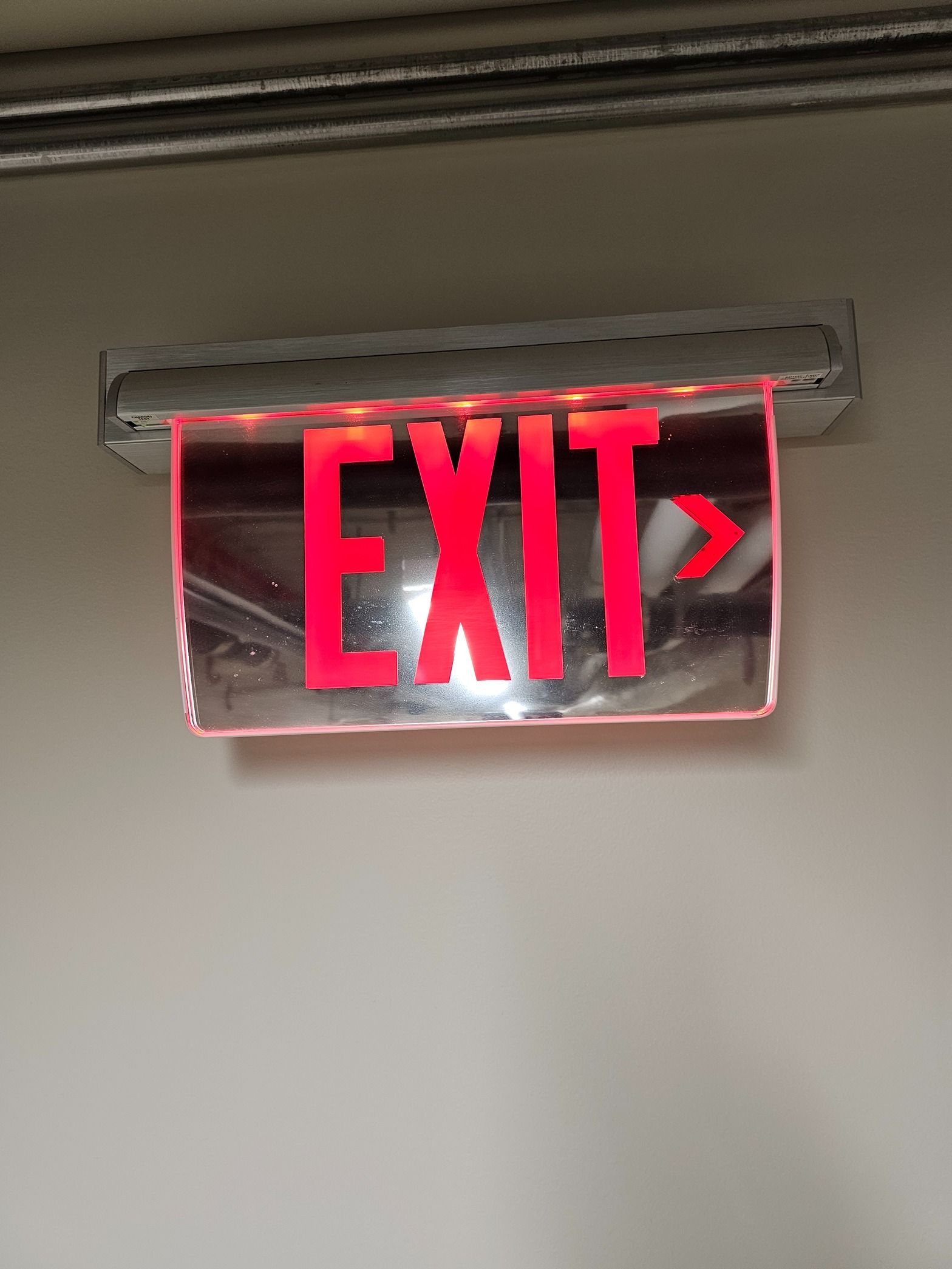 A red exit sign is lit up on a white wall