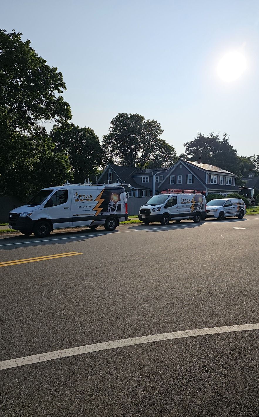 Three white vans are parked on the side of the road.