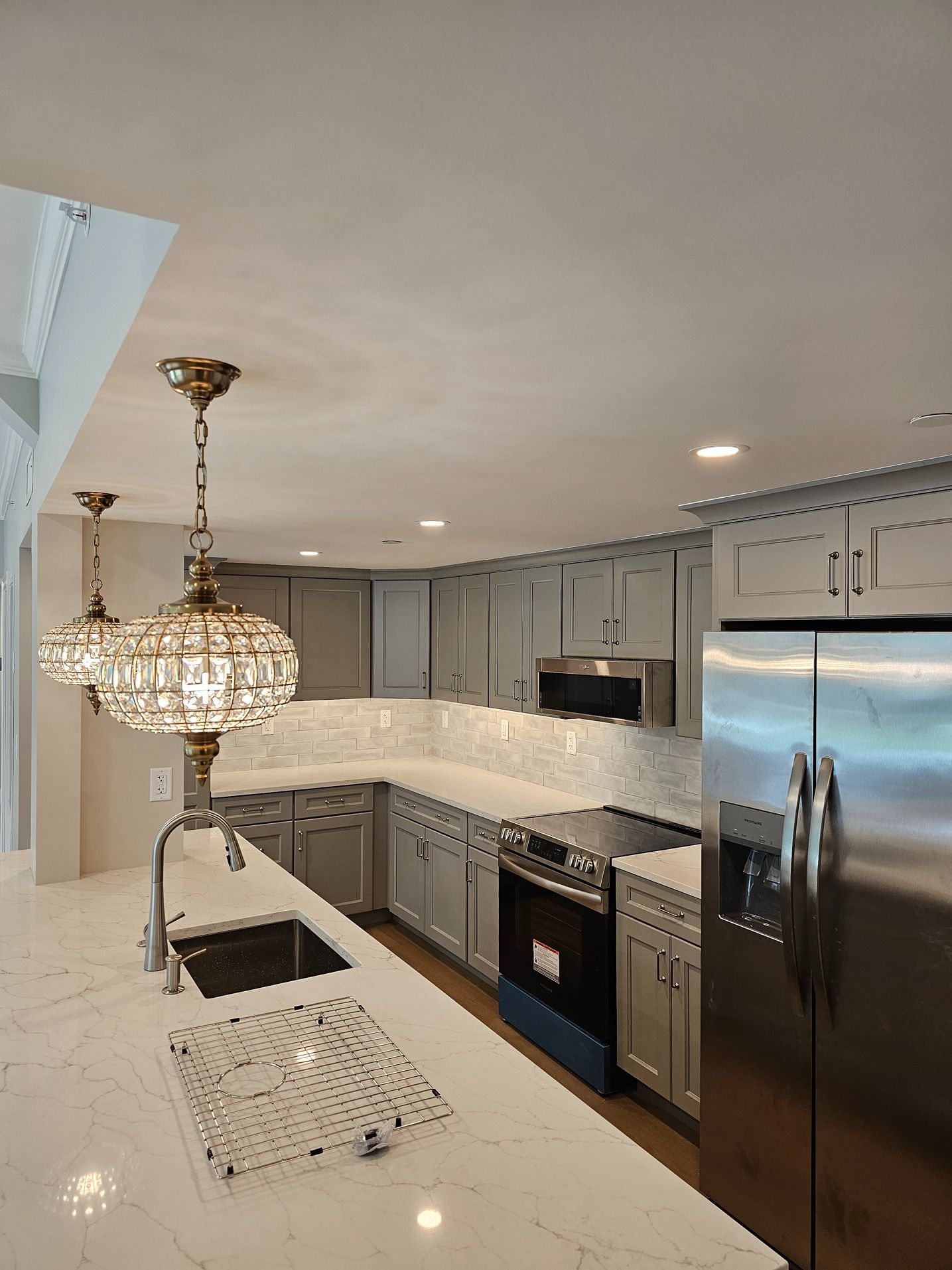 A kitchen with stainless steel appliances , a sink , and a refrigerator.