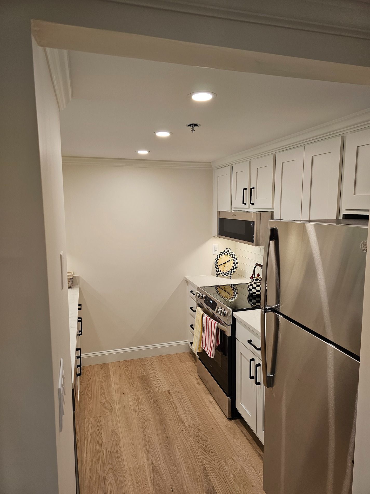 A kitchen with stainless steel appliances and white cabinets.