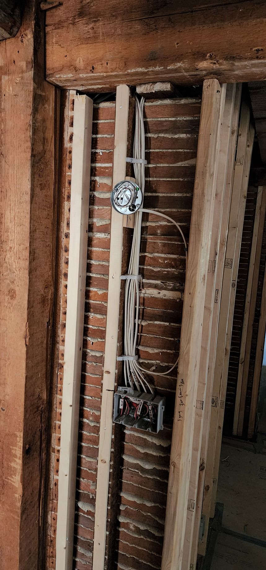 A brick wall with wooden beams and wires coming out of it.