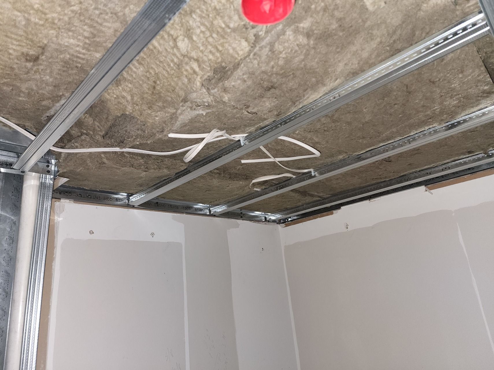 A red fire alarm is hanging from the ceiling of a room.