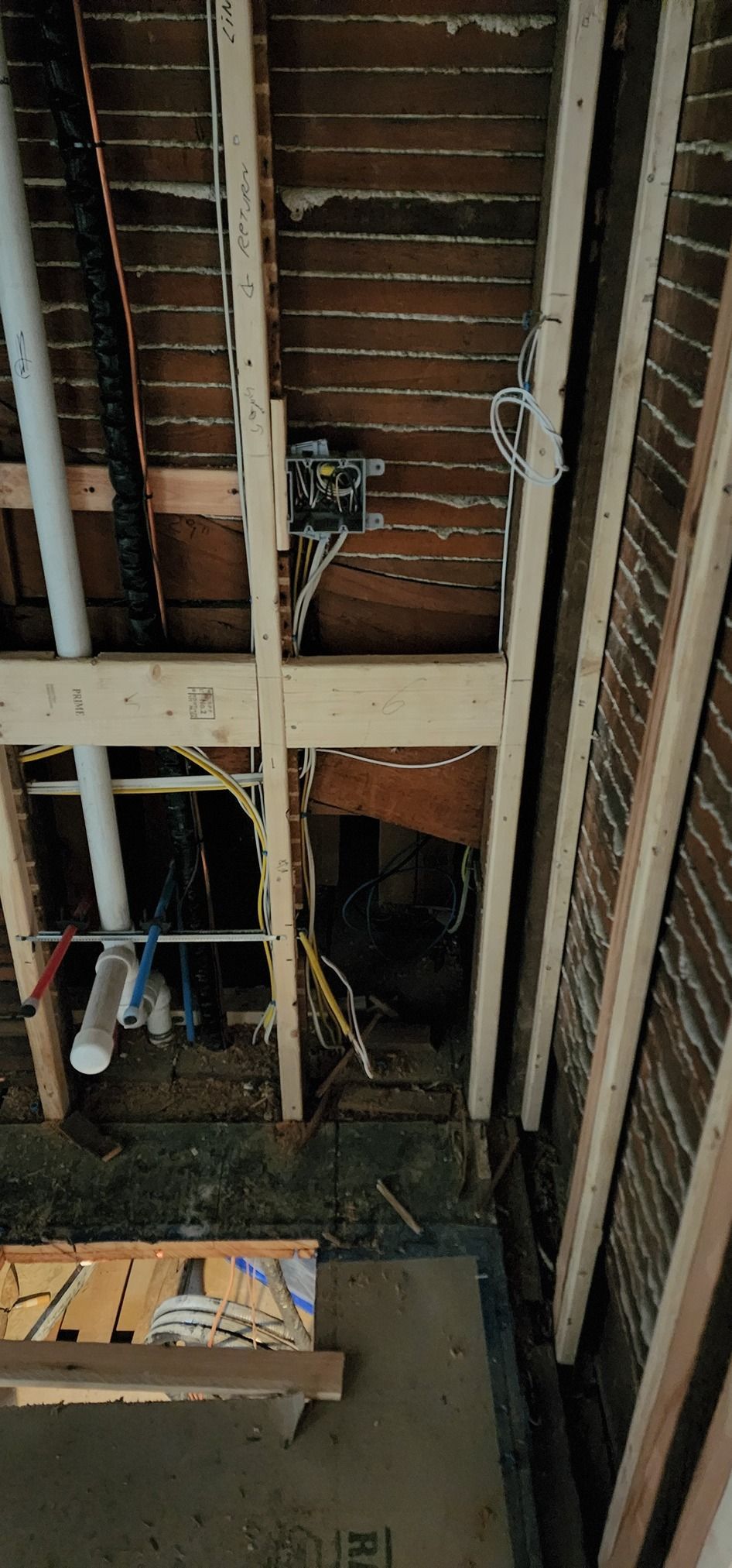 The ceiling of a building under construction with pipes and wires coming out of it.