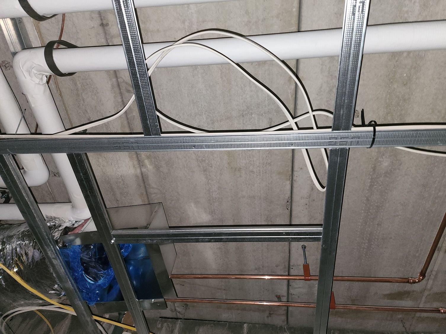 A ceiling with pipes and wires hanging from it